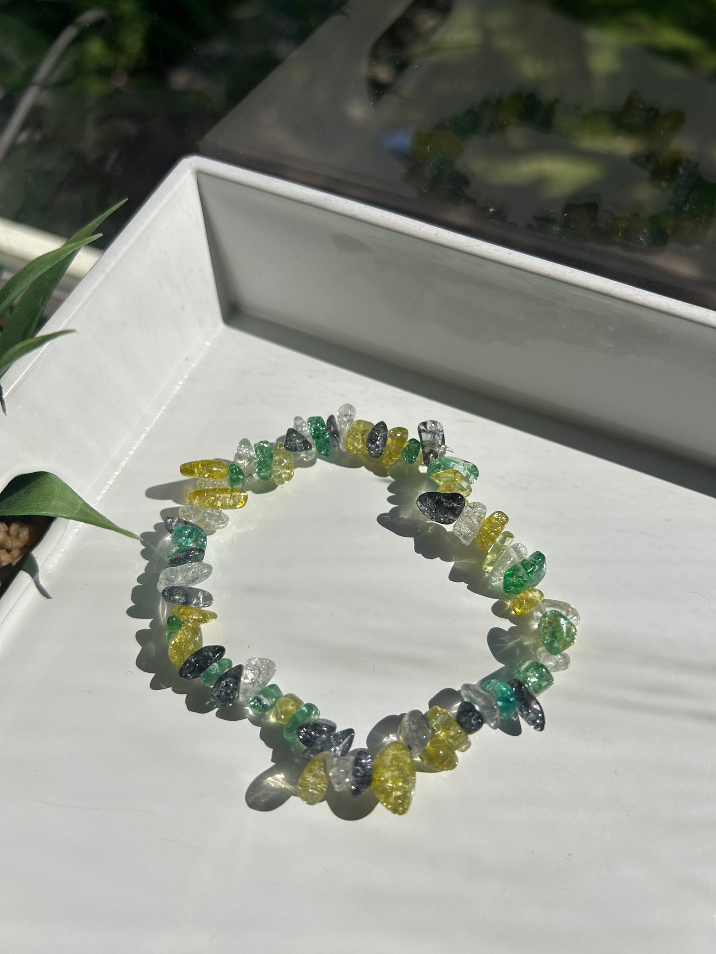 Colorful beaded bracelet on a white surface with a blurred natural background