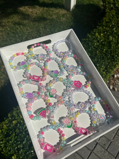 Box of colorful children beaded bracelets on a grassy background