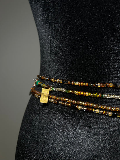 Three beaded waistbeads with a gold tag on a black background
