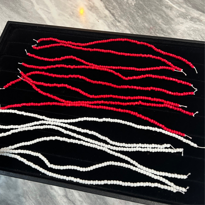Red and white braided hair extensions on a black tray with a marble background.