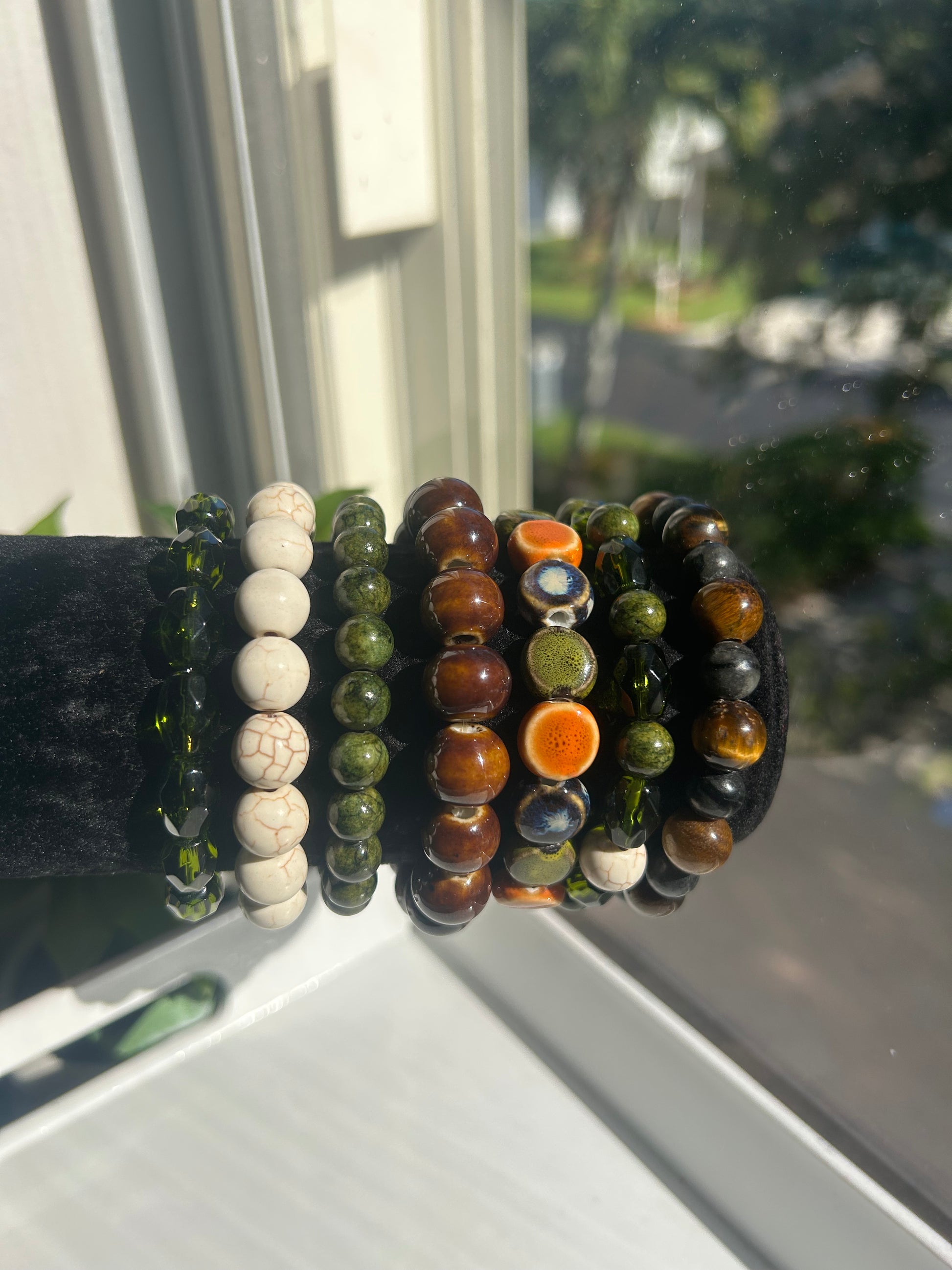 Set of natural beaded bracelets on a black velvet background with a reflective surface.